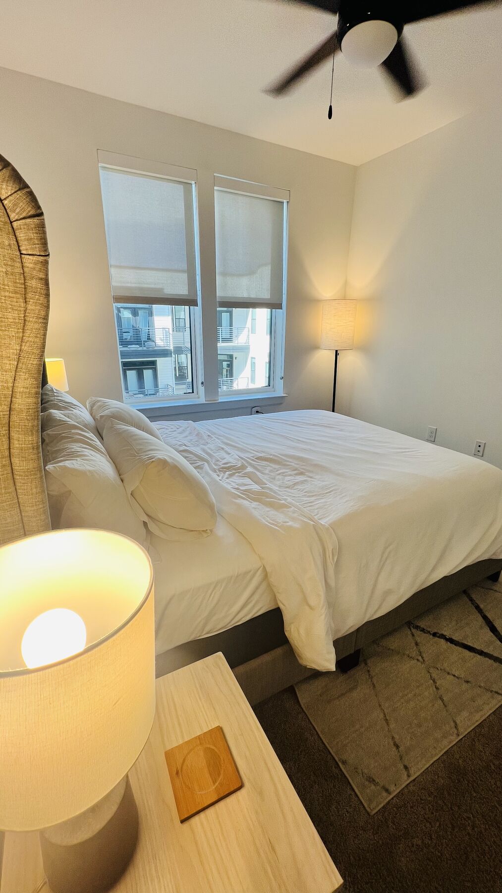 Bedroom with plush king bed, ceiling fan, and natural light from large windows