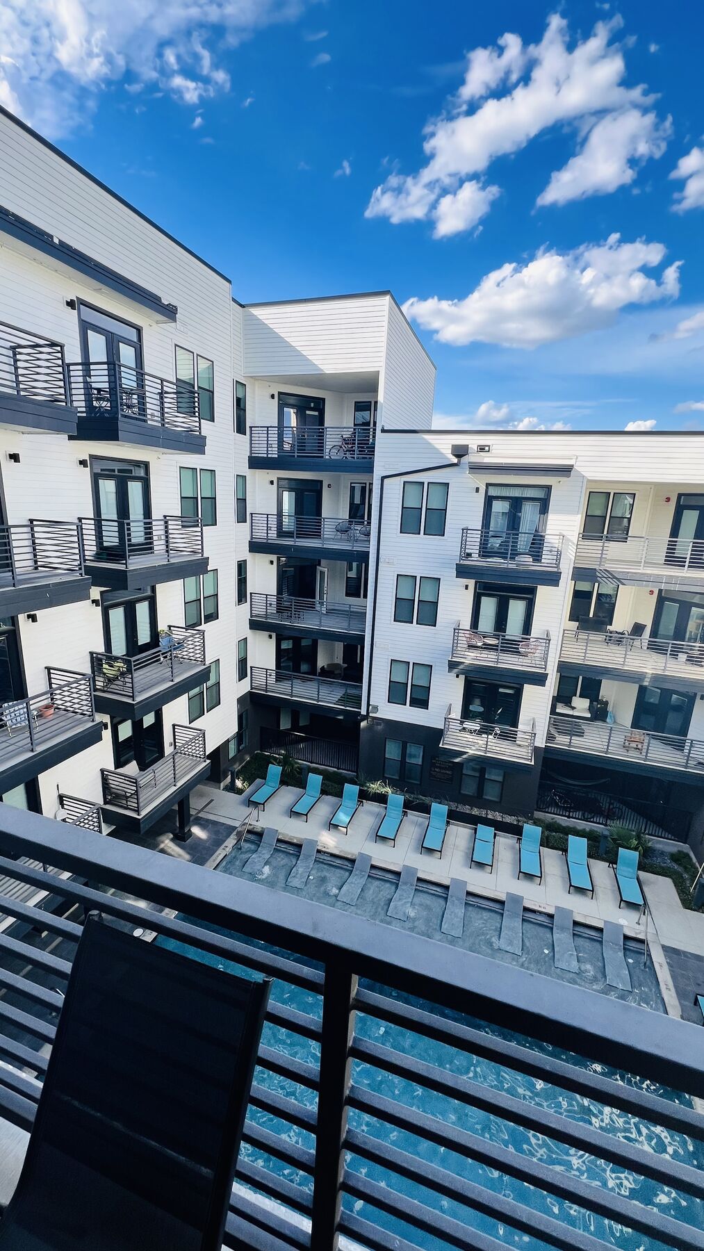 View of the building's courtyard pool and balconies under a blue sky